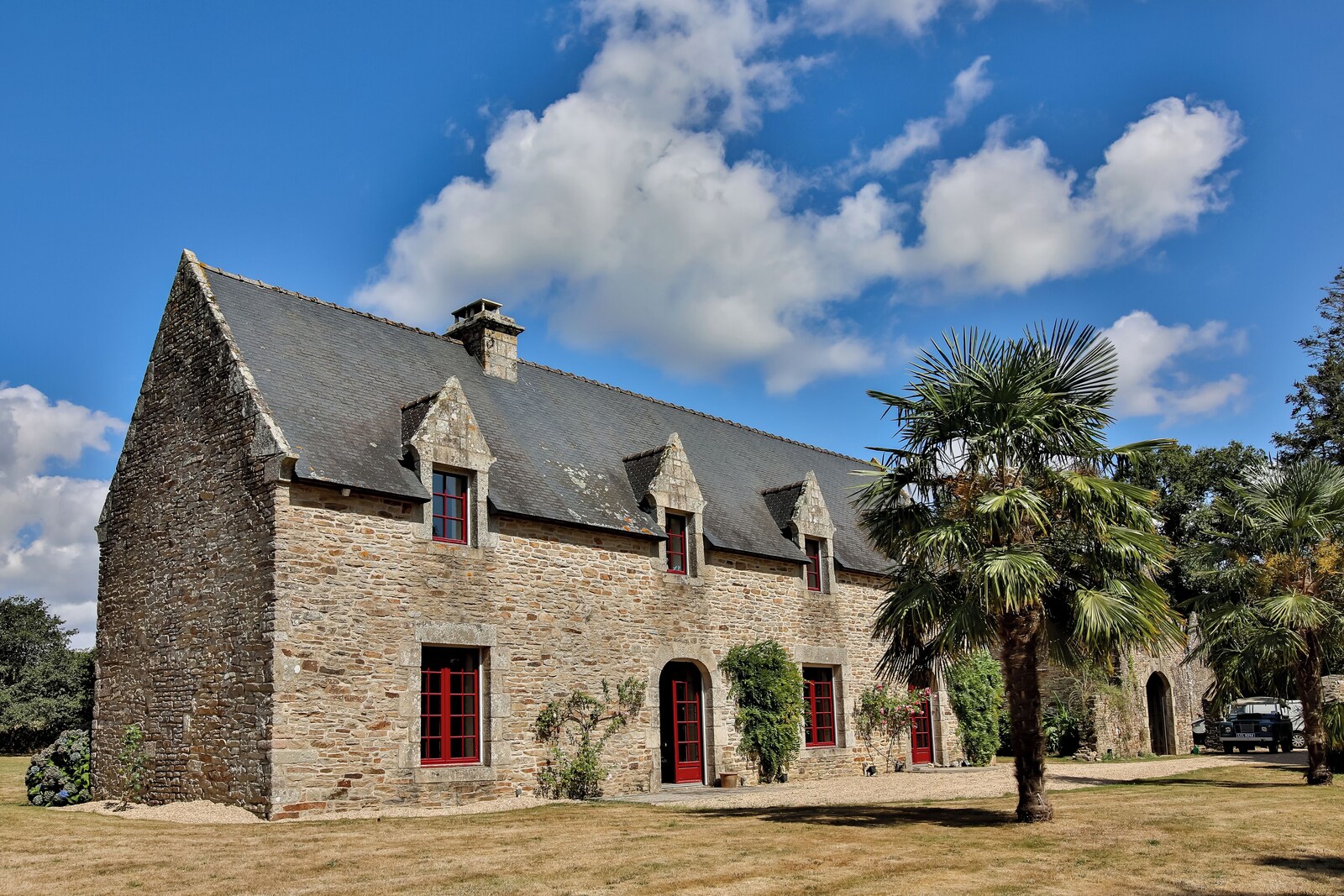La façade en pierre et ses fenêtres rouges